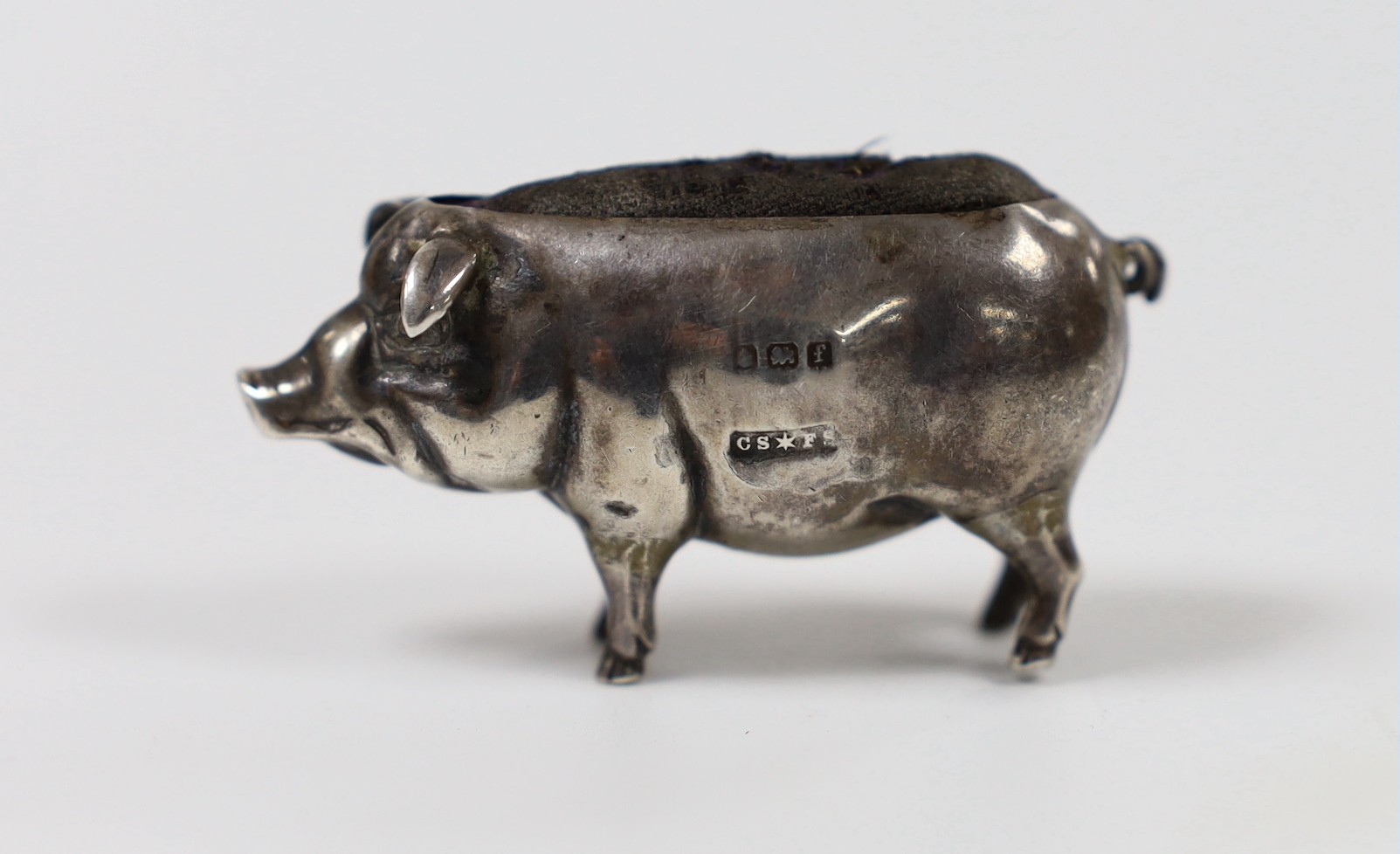 An Edwardian novelty silver mounted pin cushion, modelled as a pig, Saunders & Shepherd, Birmingham, 1905, length 47mm.